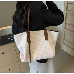 Detail showing white woven texture and brown shoulder strap of a large capacity tote bag