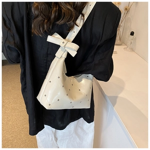 Détail du sac bandoulière en cuir PU crème avec rivets argentés et un grand nœud décoratif