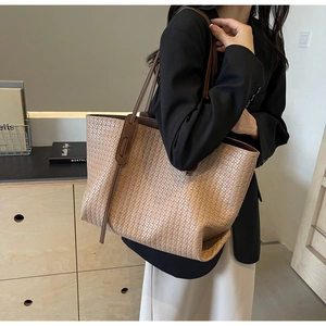 Detail of khaki woven tote bag with slim brown handles showing large capacity texture