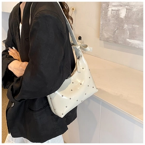 Détail du sac à bandoulière matelassé beige en similicuir avec rivets et bandoulière nouée