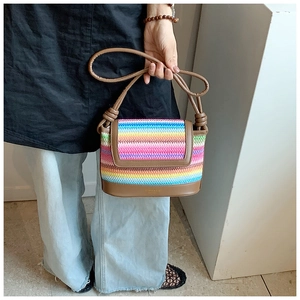 Détail du sac à main en paille arc-en-ciel avec bandoulière en cuir brun et poignée nouée