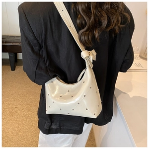 Détail du sac à main matelassé beige crème avec rivets argentés et bandoulière à nœud