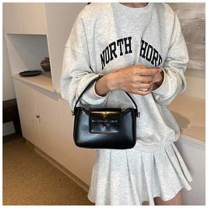 Detail view of the black PU leather handbag featuring a stylish decorative bow and flap closure
