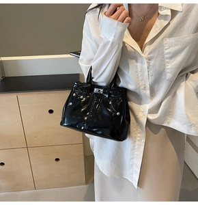 Détail d'un sac à main en cuir verni noir avec boucle et poignée en métal argenté brillant