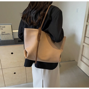 Detail of a large woven PU leather tote bag in beige coffee tone on model's shoulder