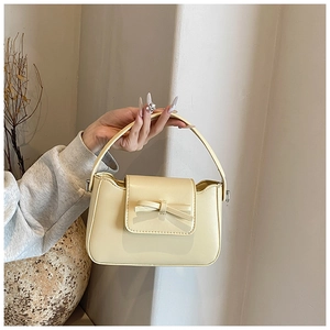 Detailed view of cream PU leather handbag featuring an elegant matching bow decoration