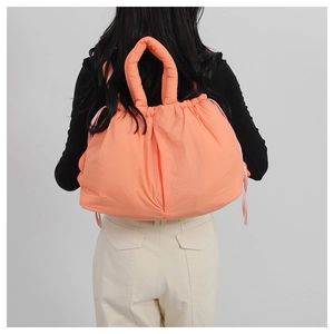 Detail of orange puffer tote bag with pink drawstring accents and lightweight padded texture