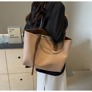 Detailed close-up of woven texture and slender leather straps on a large tote bag
