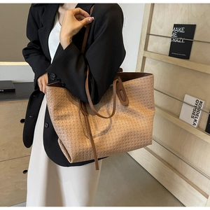 Close-up of khaki woven PU leather tote bag with brown handles in a fashion lifestyle setting