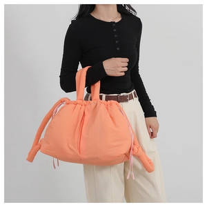 Bright orange quilted nylon tote bag shown on model for a large capacity casual look
