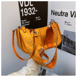 Détail du sac croissant orange métallisé montrant les clous argentés sur la bandoulière