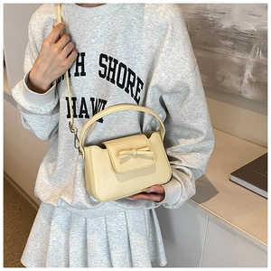 Detail view of cream yellow PU leather bag with bow decoration on stylish grey sweatshirt