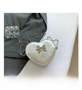 Detailed close-up of heart-shaped silver metallic mini bag with a rhinestone bow knot decoration