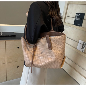 Detail of a large woven tote bag with beige grid texture and brown leather shoulder straps