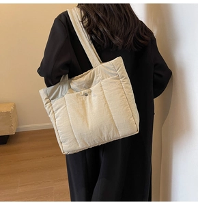 Detail of beige quilted tote bag showing padded texture and external snap pocket