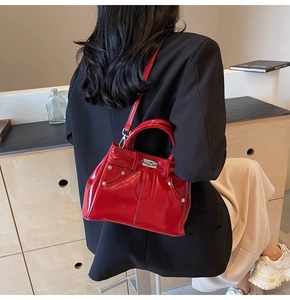 Détail du sac à main en cuir verni rouge avec rivets argentés et design style denim
