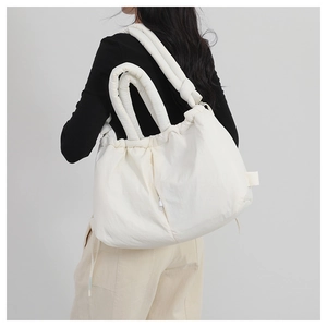 Detailed macro view of white quilted puffer tote bag with thick padded shoulder straps