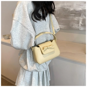 Close-up of a stylish cream yellow PU leather crossbody bag with a cute bow detail