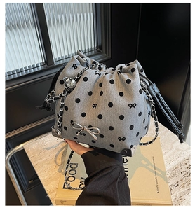 Detail of grey polka dot drawstring bucket bag with silver bow and chain strap