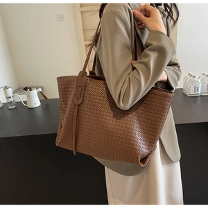Detailed side view of brown woven tote bag on model showing large capacity and texture