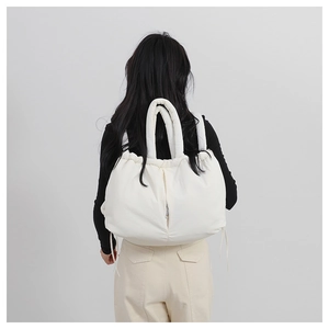 Rear view of a person wearing a white quilted puffy backpack with metal zipper detail