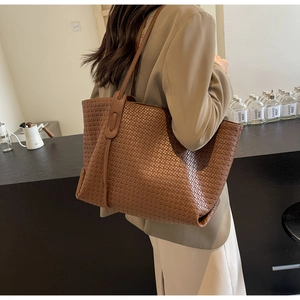 Close-up of a brown woven PU leather tote bag with a checkered pattern carried by a model