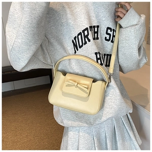 Detail showing cream PU leather crossbody bag with bow decoration and adjustable strap