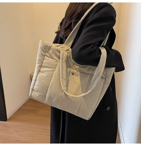 Detailed side view of beige quilted puffer tote bag with silver magnetic closure