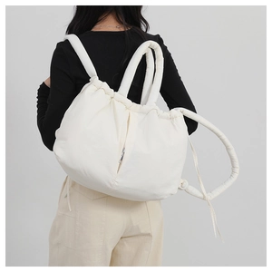 Close-up of a white quilted puffer backpack with soft padded straps on a model