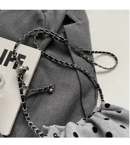 Detail of silver metal chain strap with adjustable gold ball buckle on polka dot fabric bag
