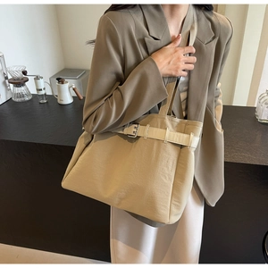 Chic beige fabric tote bag with leather belt detail shown on model in cafe setting