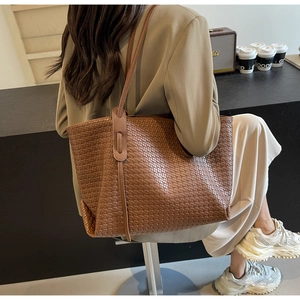 Close-up of brown woven PU leather tote bag with stylish fringe details and long handles