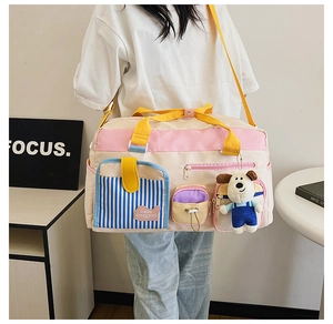 Detail einer beigen Nylon-Reisetasche mit bunten Taschen und einem Plüsch-Hundeanhänger