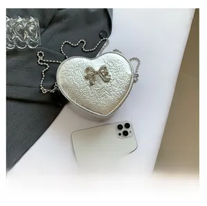 Top view of silver heart-shaped PU leather crossbody bag with rhinestone bow and bead chain