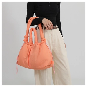 Detail of coral orange padded tote bag featuring side drawstring design and knotted handle