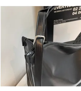Detail of adjustable long shoulder strap with silver square metal buckle on black leather bag