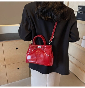 Détail macro du sac à main en cuir verni rouge avec rivets sur fond de bois