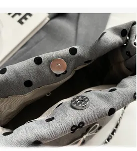 Close-up of grey herringbone fabric bag with silver magnetic snap and chain strap