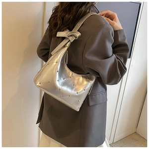 Détail du sac sous le bras argenté avec surpiqûres matelassées et rivets