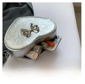 Detail view of silver heart crossbody bag with bow, showing interior capacity for essentials