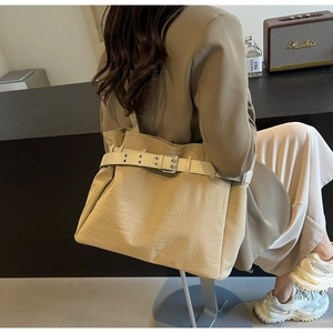 Close-up of beige fabric tote bag with leather strap and metal buckle detail