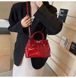 Détail du sac à main en cuir verni rouge avec rivets métalliques et bandoulière sur mannequin