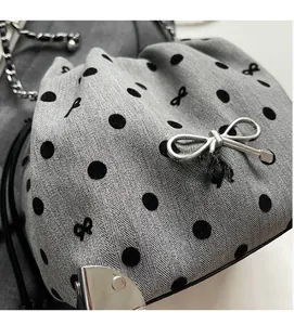 Detailed view of grey polka dot fabric bag with silver bow charm and metal chain