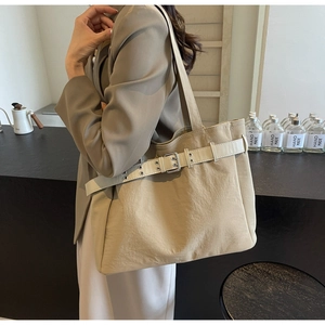 Detail of a khaki tote bag with a decorative white belt and silver buckle design