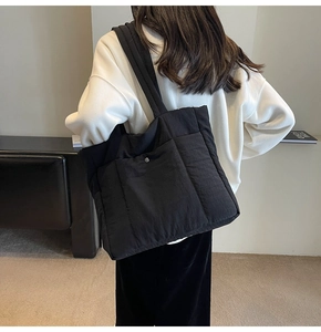 Close-up of black quilted tote bag with wide strap on a model for daily commute style