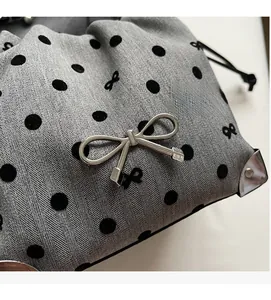 Detail of grey polka dot fabric bag with silver bow buckle and drawstring closure
