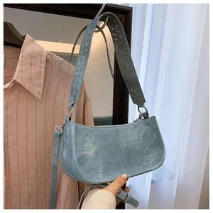 Détail du sac demi-lune bleu clair avec bandoulière à rivets et fermeture zippée