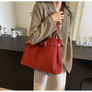 Detailed view of brick red canvas tote bag with stylish leather buckle strap decoration