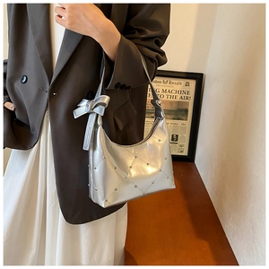 Détail du sac bandoulière argenté en similicuir matelassé avec strass et nœud décoratif