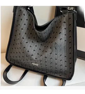 Detail of grey herringbone fabric tote bag with black bow prints and leather straps